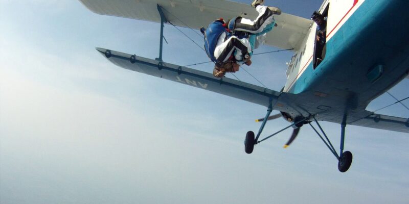 Two people in tandem skydiving freefall jumping from a plane over open sky